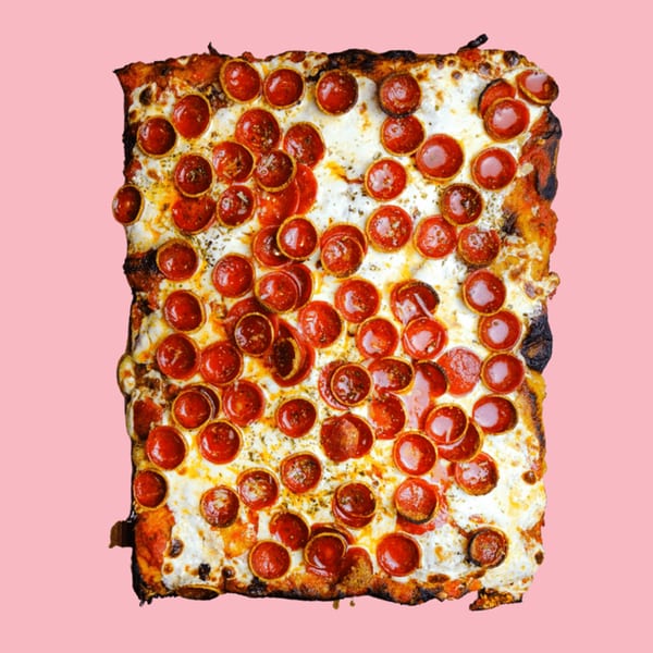 A rectangular pepperoni pizza with crispy edges and melted cheese, centered on a pink background.
