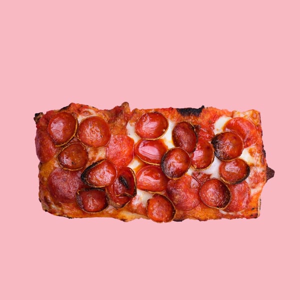 Rectangular pepperoni pizza slice with crispy edges and melted cheese on a pink background.