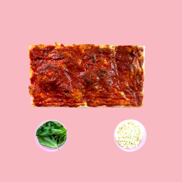 Rectangular pizza with tomato sauce, alongside bowls of fresh basil and shredded cheese.