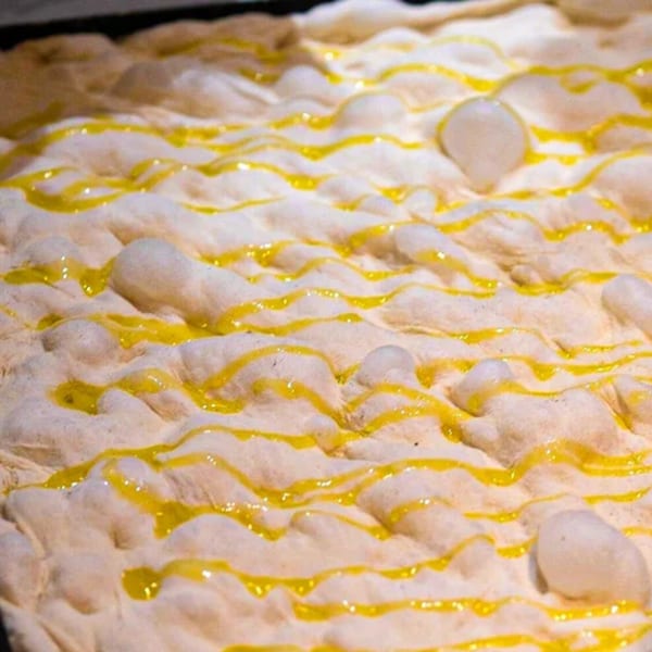 Close-up of Pizza Collective's focaccia dough, drizzled with olive oil before baking.