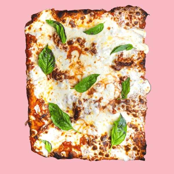 A rectangular slice of lasagna with melted cheese and fresh basil leaves on a pink background.